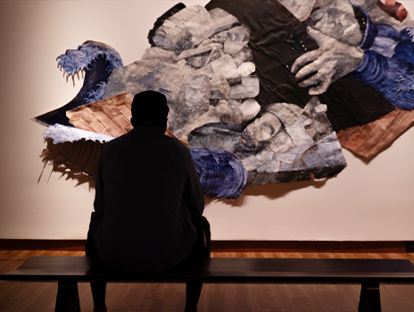 A family, including a woman and two boys, looks at informational papers while visiting an art gallery or museum.